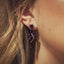 A woman showcases stunning purple amethyst earrings, adding elegance and sophistication to her outfit for any occasion.